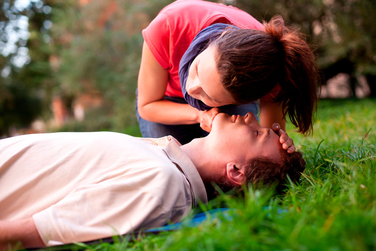 une femme écoute la respiration d'un homme à terre