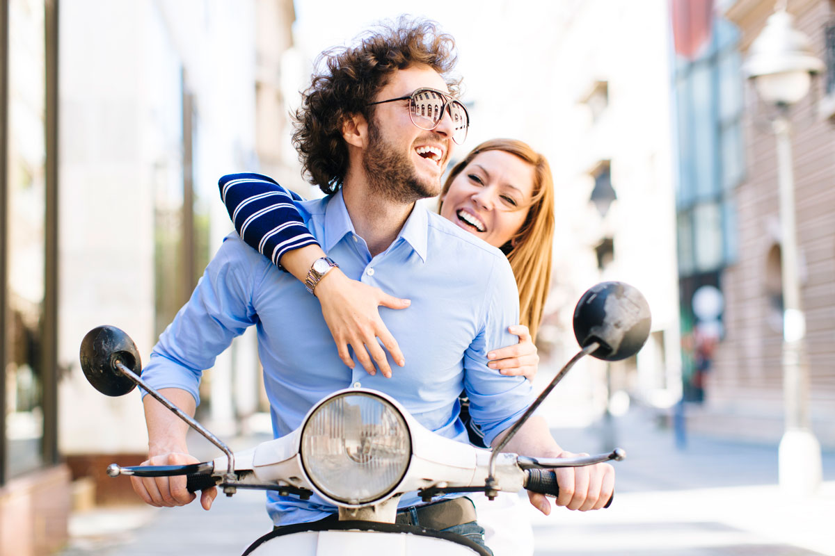 un coule au sourire forcé sur un scooter