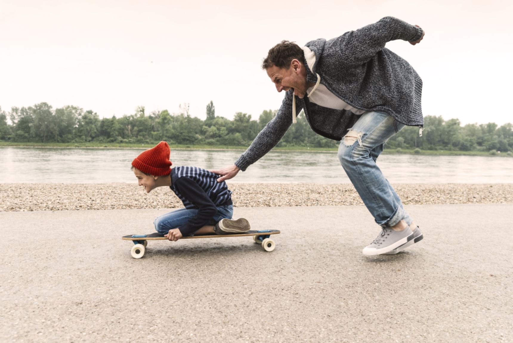 Un père pousse son fils sur un skateboard